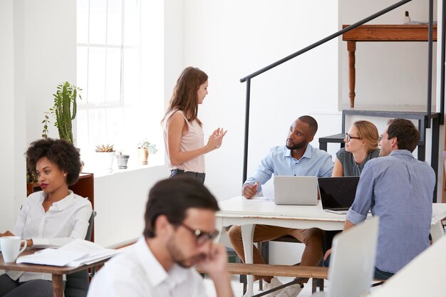 Colleagues in discussion around a desk in open plan office