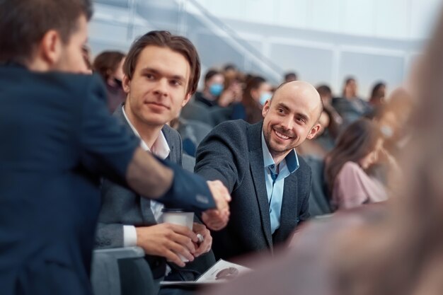 Photo colleagues greeting each other before the start of the business seminar