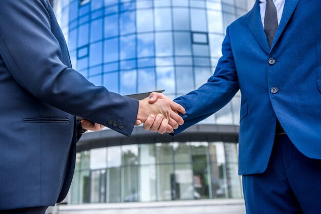 Colleagues handshaking before office building outdoors close up