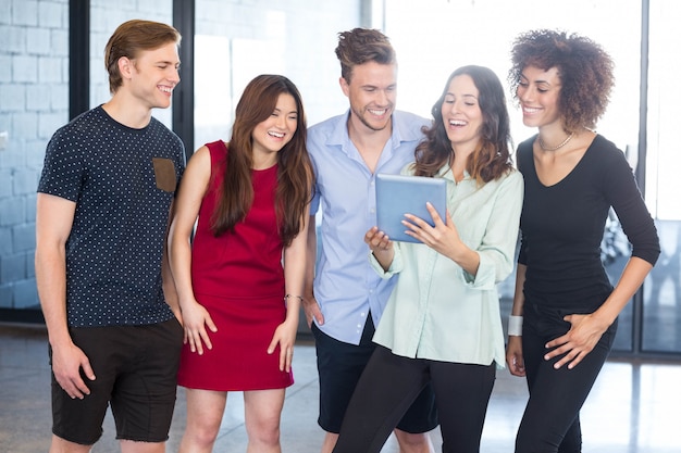 Colleagues looking in digital tablet and laughing at office