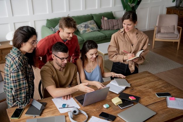 Photo colleagues looking for information using a laptop and notebooks in a study session