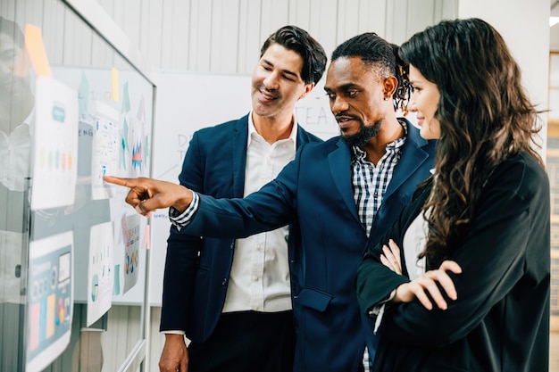 colleagues meet in the office using sticky notes on a glass board for brainstorming this diverse group exemplifies teamwork leadership and effective solutions in business discussions