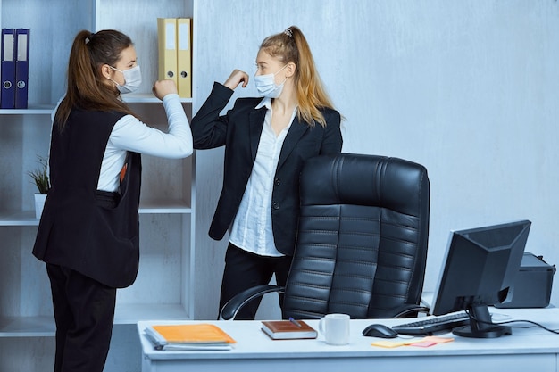 Colleagues who maintain social distance by greeting each other with elbows