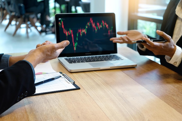 Colleagues working over stock market and exchange in laptop at office