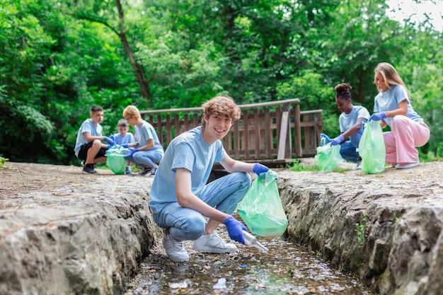 Collecting rubbish from the river Man collecting plastic rubbish on coast of the river Cleaning environment concept