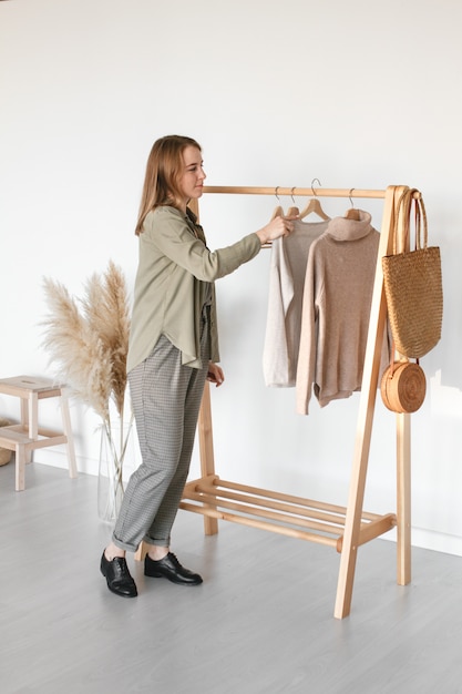 A collection of clothes, in beige tones, hanging on a hanger in the dressing room. Natural material.