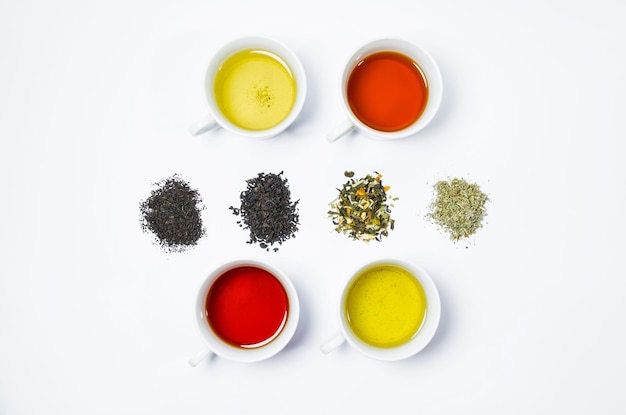 Collection of different teas in cups with tea leaves on a white background.