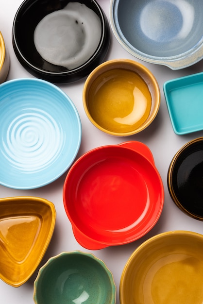 Collection of empty colorful ceramic bowls. Group of utensils captured from above, top view, flat lay against white background