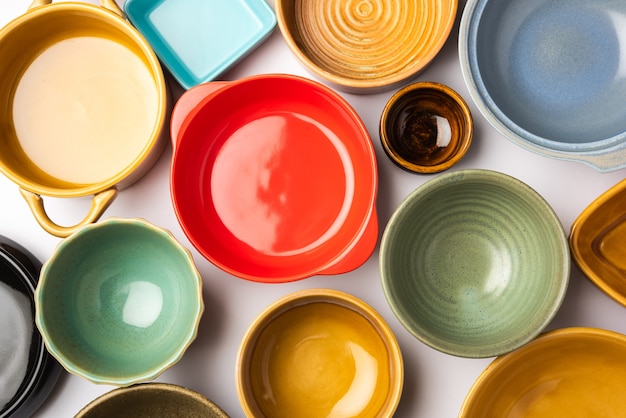 Collection of empty colorful ceramic bowls. Group of utensils captured from above, top view, flat lay against white background