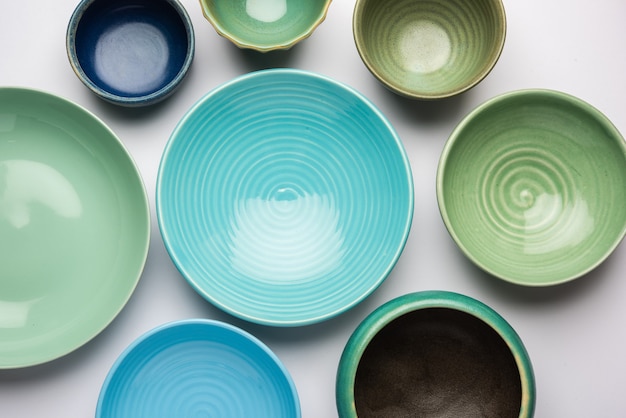 Collection of empty colorful ceramic bowls. Group of utensils captured from above, top view, flat lay against white background