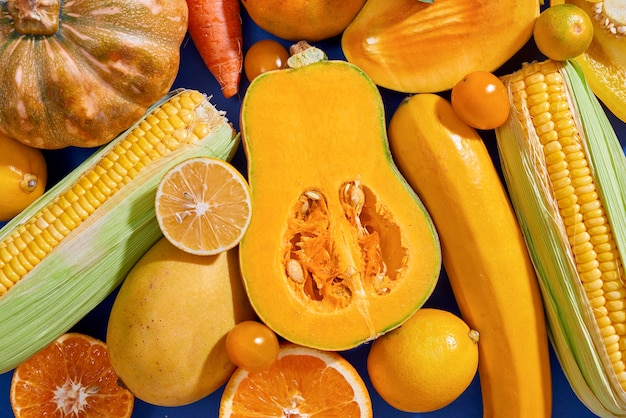 Сбор свежих желтых фруктов и овощей на синем фоне