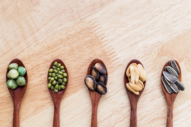 collection of grains in wooden spoon on wood background.