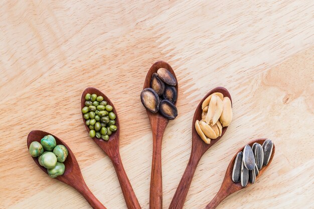 collection of grains in wooden spoon on wood background.