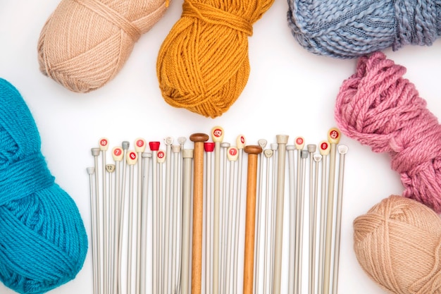 Collection of knitting needles and wool on a white\
background