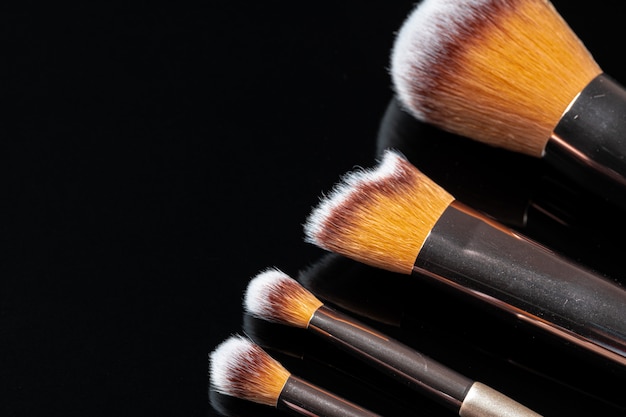 Collection of make up brushes on black background