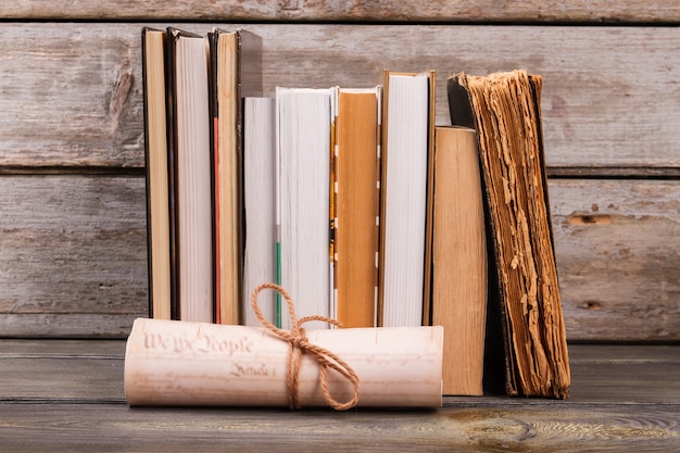 Collection of old books and scroll. Aged wooden background.