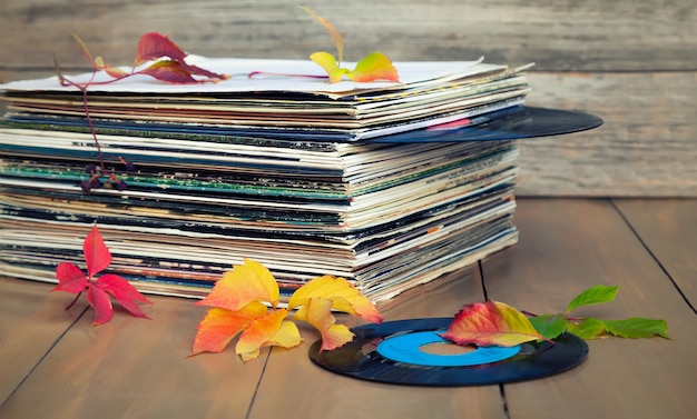 Raccolta di vecchi dischi in vinile in una pila con foglie di autunno.