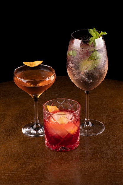 Collection of refreshing cocktails and drinks involving negroni martini whiskey and glass of white wine with ice berries and mint against a black background at an angle