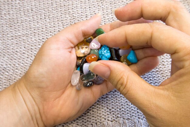 Collection Of SemiPrecious Gemstones in woman hands on blurred grey knitted background