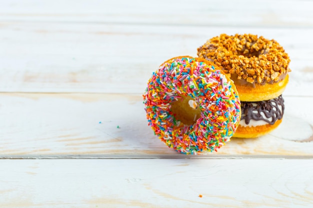 Collection of tasty donuts on white wooden board