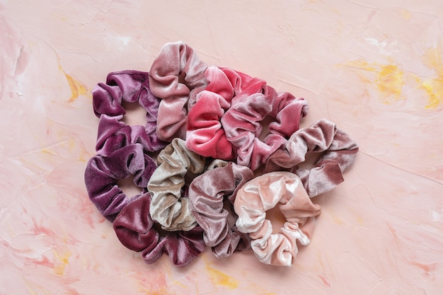 분홍색 배경에 유행 벨벳 scrunchies의 컬렉션입니다. DIY 액세서리 및 헤어 스타일 개념, 복사 공간