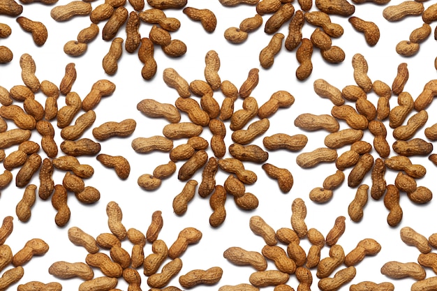 Собрание нерафинированных арахисовых орехов лежит в форме круга или солнца на изолированной белой стене. Сырой Арахисовый Образец