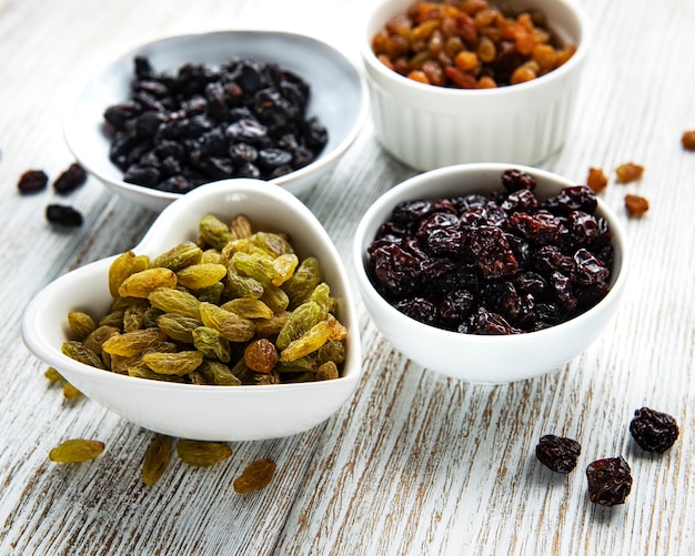 Collection of various raisins on a white wooden background