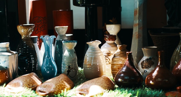 A collection of vases are on a table with a green grass background.