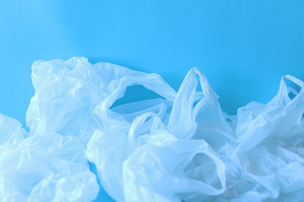 Collection of white disposable plastic bags on blue background. Plastic waste concept.