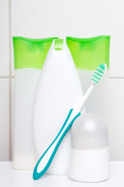 collection of white and green cosmetic bottles over tiled wall in bathroom