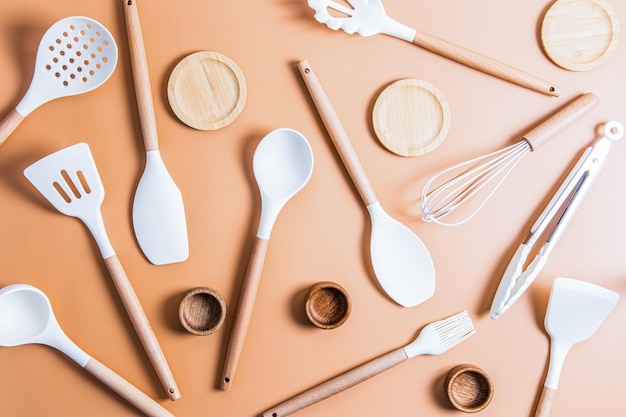 A collection of white silicone tools for cooking food in the kitchen top view flat styling beige background