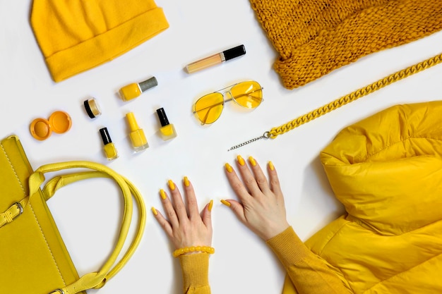 여성과 함께하는 노란색 세련된 옷장 항목 모음은 손입니다.