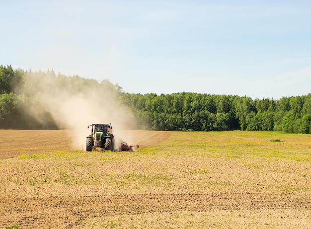 Collective farmers sow sow crops in the field big tractor working in the field harvesting doing business farming soil preparation for planting