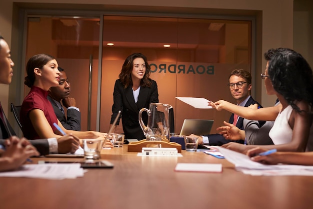 Collega die een document doorgeeft tijdens een zakelijke bijeenkomst onder een lage hoek