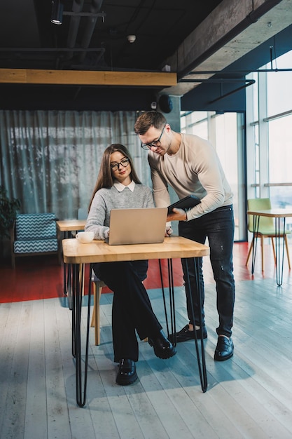 Collega's delen hun ervaring met het werken op kantoor bij een laptop Bespreking van het werkplan van kantoorwerkers