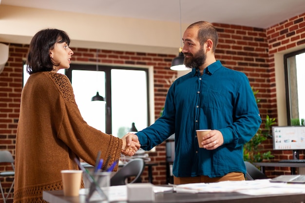 Foto collega's die handen schudden die bij een financieel project werken en samen bedrijfsinvesteringen plannen in een startkantoor. ondernemers die marketingdocumenten analyseren die naar het strategierapport kijken. bedrijfsconcept