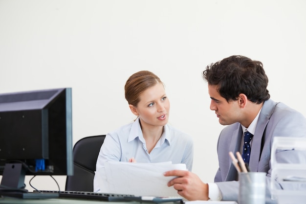 Collega&#39;s die terwijl het houden van een blad spreken