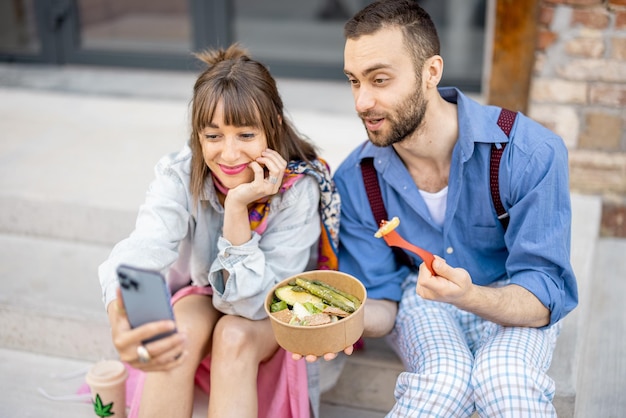 Collega's eten gezond afhaalmaaltijden en praten buiten aan de telefoon