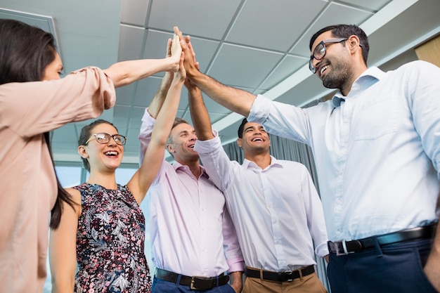 Collega's geven high five tijdens bijeenkomst in kantoor
