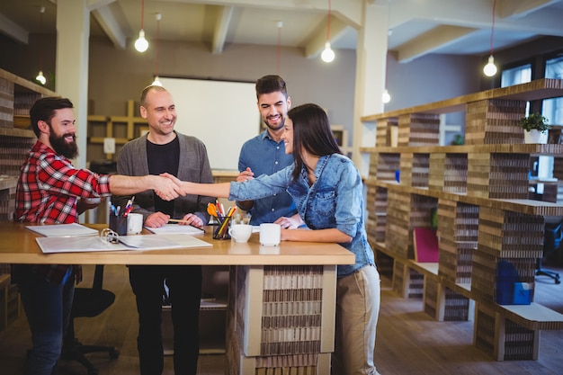 Collega's glimlachen terwijl handen schudden aan tafel