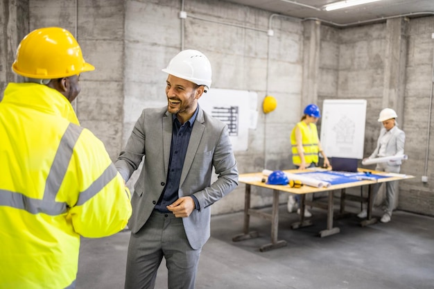 Collega's in de bouwsector schudden elkaar de hand voordat het nieuwe bouwproject van start gaat