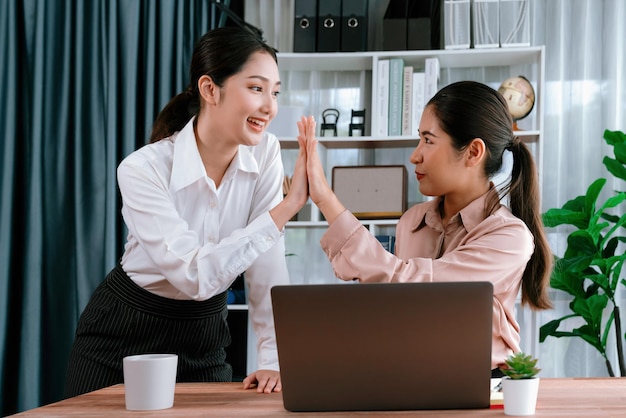 Collega's in de kantoorwerkruimte geven een highfive om te vieren dat ze een project hebben voltooid of een oplossing voor een probleem hebben gevonden, waaruit een sterk gevoel van teamwerk en vriendschap op de werkplek blijkt Enthousiast