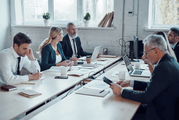 Collega's in elegante formele kleding die moderne technologieën gebruiken terwijl ze op kantoor werken