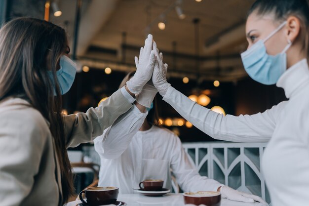 Collega's met beschermende maskers geven een high five op kantoor