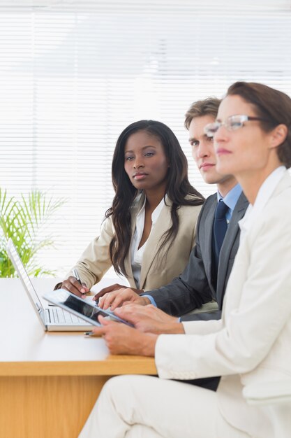 Collega&#39;s met laptop en digitale tablet in vergadering bij bureau