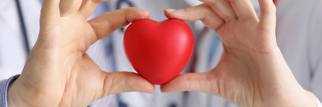 Collega's van medische werkers houden samen plastic rood hart vast