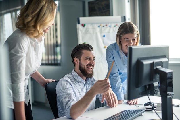 Collega's werken samen in een kantoor op een computer.