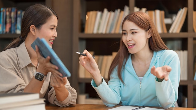 College education concept Teenage girl pointing graph on tablet to asking question with tutor