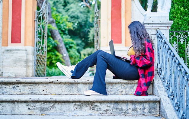 公園でノートパソコンで勉強している大学生の女の子