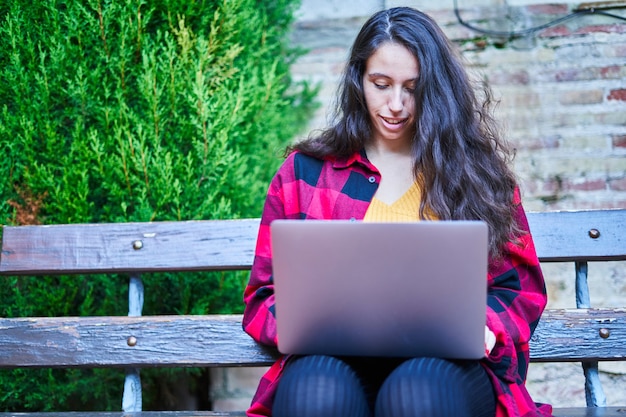 Студентка колледжа учится с ноутбуком в парке